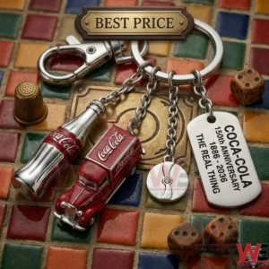 A detailed metal keychain with four charms including a soda bottle a delivery truck and an anniversary tag! It lies on a colorful tiled background with a thimble and dice!