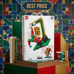 A retail box for a soccer themed building set sits on a shelf next to books and a mug with a mosaic wall behind it.