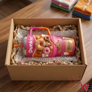 The pink Dunkin anniversary tumbler is securely packed with bubble wrap and paper inside an open cardboard shipping box on a wooden table.