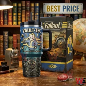 A high angle shot of a Fallout themed insulated tumbler with a handle and straw next to its box on a wooden desk! The tumbler has blue and grey sections with embossed details! Office supplies and a globe are also visible!