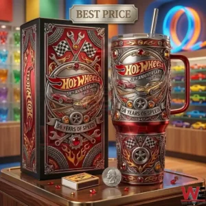 A close up photograph of a Hot Wheels anniversary tumbler and its original packaging box on a wooden desk! The tumbler has intricate silver and red designs! Small car accessories and a coin are placed around the products!