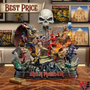 A detailed photo of a large collectible diorama statue featuring a battle between a winged creature and a red devil, with the large text IRON MAIDEN at its base. The scene is complex with many figures and textures. It sits on a wooden shelf with other collectible figures and album art in the blurred background.