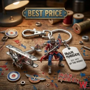 A close up photograph of an Iron Maiden themed keychain with a biplane charm and an Eddie figure! The keychain is surrounded by music pins and sewing spools on a wooden desk with paint marks!
