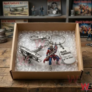 A high angle view of an Iron Maiden keychain inside a cardboard box with bubble wrap! The charms are neatly presented against the white packaging! The background shows a collection of model kits and band memorabilia!