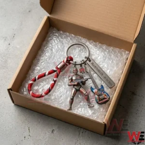 A heavy metal keychain with a cyborg figure and a guitar charm resting on bubble wrap inside an open cardboard box!