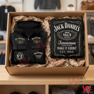 A black Jack Daniels branded hoodie folded inside a cardboard shipping box with brown packing paper on a wooden shelf.