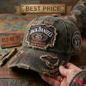 A weathered dark denim cap with frayed Jack Daniels branding patches and embroidery is shown in a close up view on a wooden surface!
