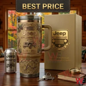 A celebratory tan tumbler with embossed vehicle graphics and dates sits next to its display box and travel gear on a desk!