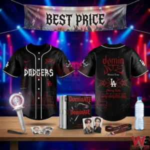 Front and back view of a black Stray Kids Dodgers jersey with red and white graphics displayed with a light stick and merchandise on a wooden table!