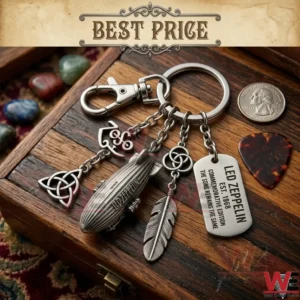 A close up photograph of a Led Zeppelin commemorative keychain with five charms on a wooden surface! The charms include a blimp an engraved tag a feather and band symbols! A coin and a guitar pick are placed nearby!