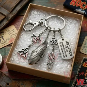 An overhead view of a Led Zeppelin keychain inside a shipping box with protective bubble wrap! The charms are neatly arranged for display! The background shows a wooden table with vintage music memorabilia!
