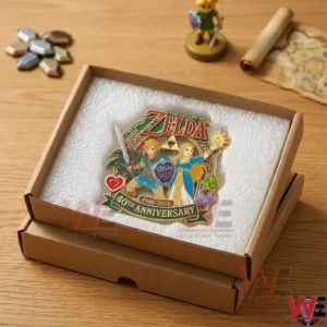 A high angle shot of a Zelda anniversary pin protected by foam inside a cardboard shipping box on a wooden desk!