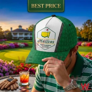 A man in a striped shirt pulling down the brim of a green and white tournament golf cap with a drink and golf glove on the table!