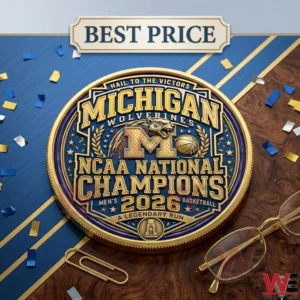 A blue and gold Michigan Wolverines national championship coin displayed on a wood and blue surface with glasses and confetti.