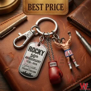 A detailed close up of a silver Rocky anniversary keychain with a boxing glove charm and a miniature boxer figurine on a brown leather diary!