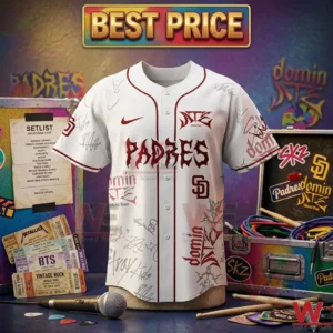 Front view of a white Stray Kids Padres jersey with red and grey graphics displayed with concert merchandise and stage equipment!