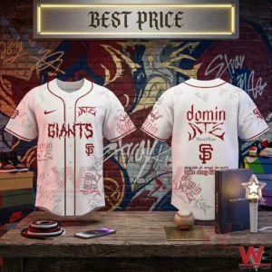 Front and back view of a white Stray Kids Giants baseball jersey with red graphics and signatures on a wooden desk in front of a graffiti wall!
