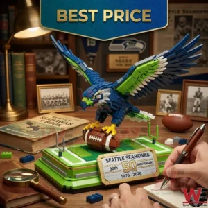 A close up photograph of a Seattle Seahawks building set featuring a blue and green osprey holding a football! The model stands on a miniature field base with an anniversary plaque! A hand holding a pen and several books are in the background!