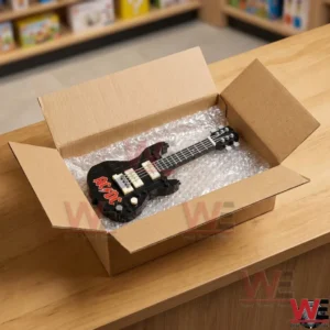 ACDC Highway to Hell Back In Back Guitar Brick Set 3 Opened cardboard box containing a small block toy guitar protected by bubble wrap on a wooden counter!