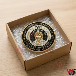 Alan Osmond Legend Memorial Coin 5 An open brown cardboard box with bubble wrap holds a detailed gold commemorative coin of Alan Osmond on a wooden table!