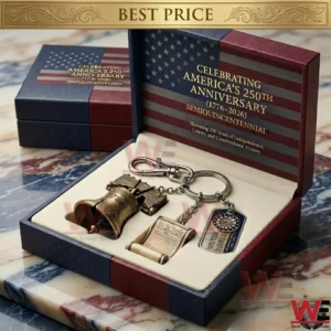 An opened commemorative gift box for the american 250th anniversary contains a bronze liberty bell miniature a small cannon and a keychain with a rolled constitution scroll and a miniature flag dog tag! Gold text is on the box lid! A closed box is behind it!