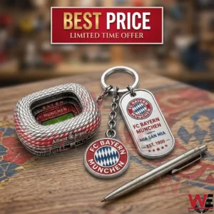 A miniature stadium model and football club logo keychain on a wooden desk.