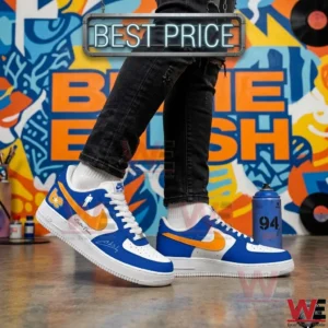 Person taking a step in black trousers and custom blue and white sneakers in an urban setting with graffiti.
