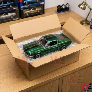 A green diecast 1967 Mustang fastback model car sitting inside an open cardboard shipping box with bubble wrap.