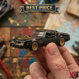 A hand holding a black and gold Pontiac Firebird Trans Am toy car.