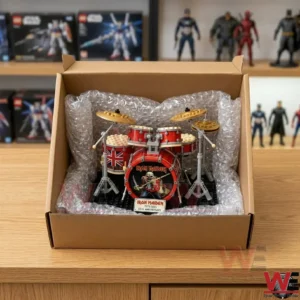 Small brick model kit of a themed drum set packed into a cardboard shipping box with protective padding on a wood surface!