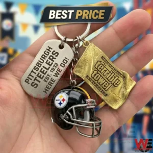Hand holding a Pittsburgh Steelers keychain with a helmet, a dog tag, and a Terrible Towel charm.