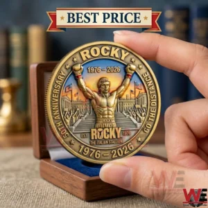 A hand holding a golden Rocky movie commemorative coin with a boxer design.